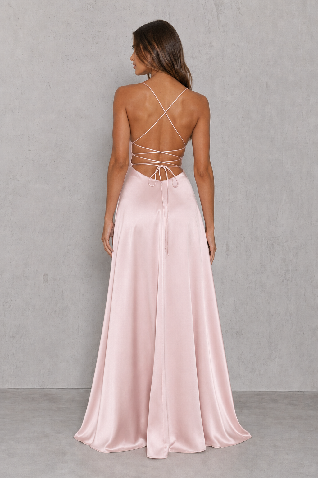 Woman wearing a pink evening gown with a strappy back design against a gray background
