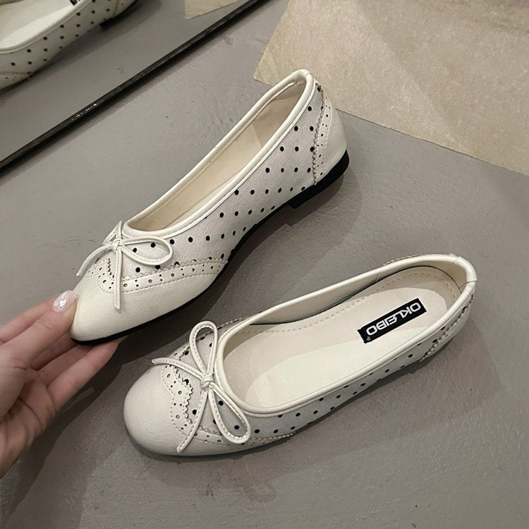 White flat shoes with lace details on a gray surface, brand 'OXFORD' visible.