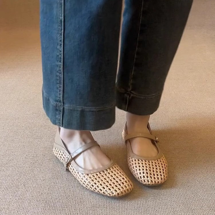 Person wearing beige woven flats with rolled-up jeans on a neutral carpeted floor.