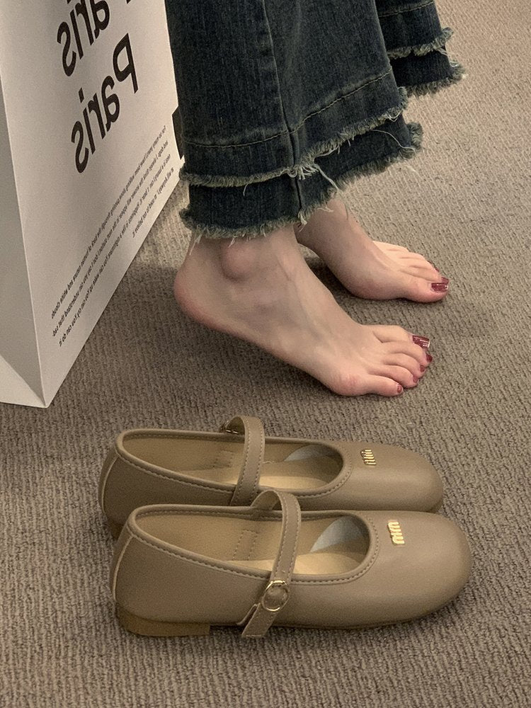 Beige shoes on a carpeted floor with a person wearing jeans and bare feet.