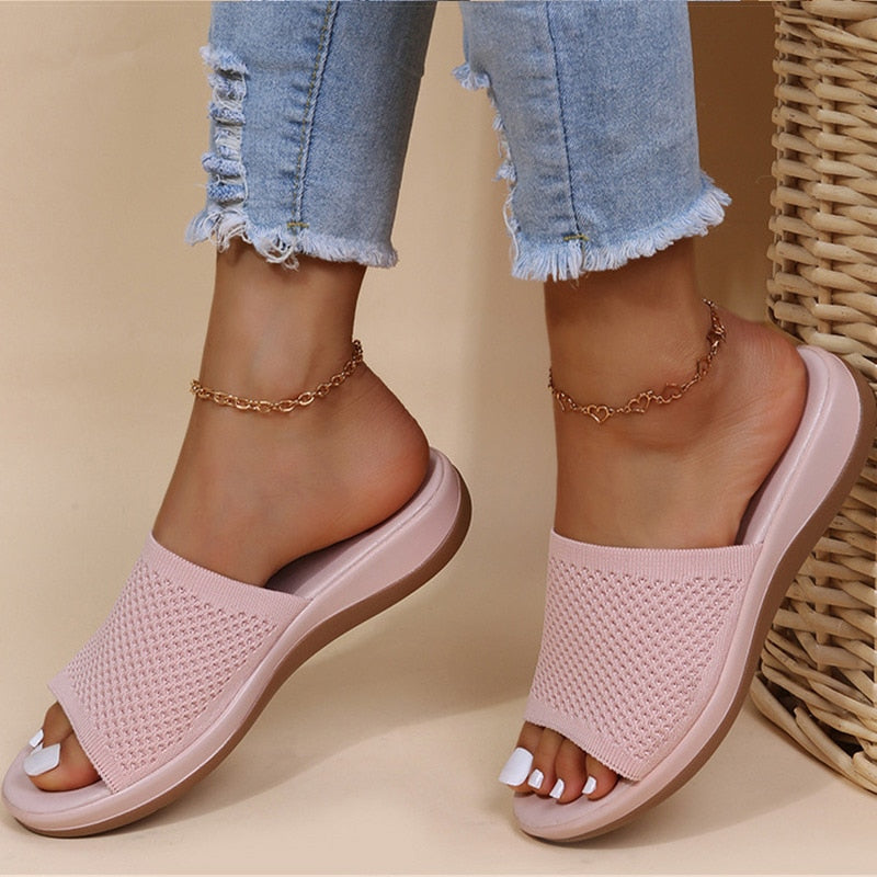 Pink open-toe sandals worn with light blue jeans on a beige background