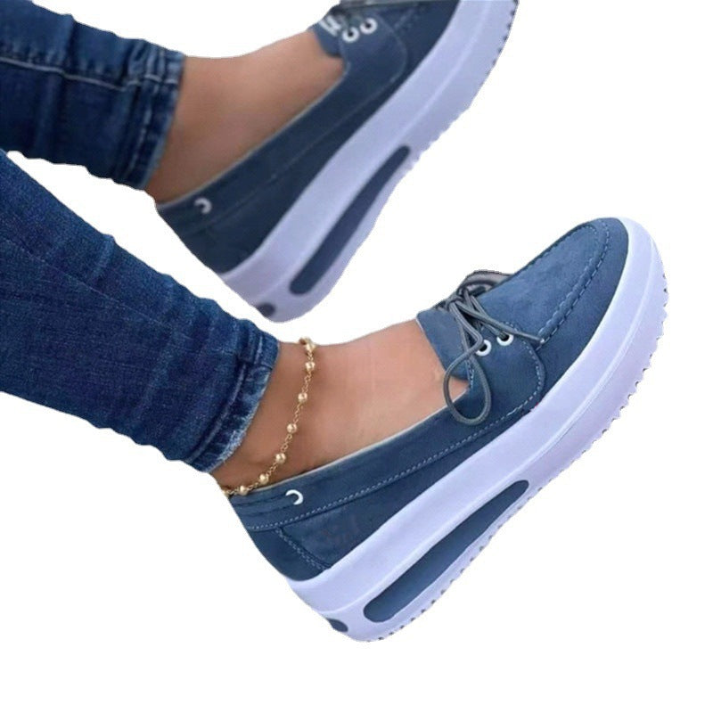 Blue casual shoes with white soles worn with jeans on a white background