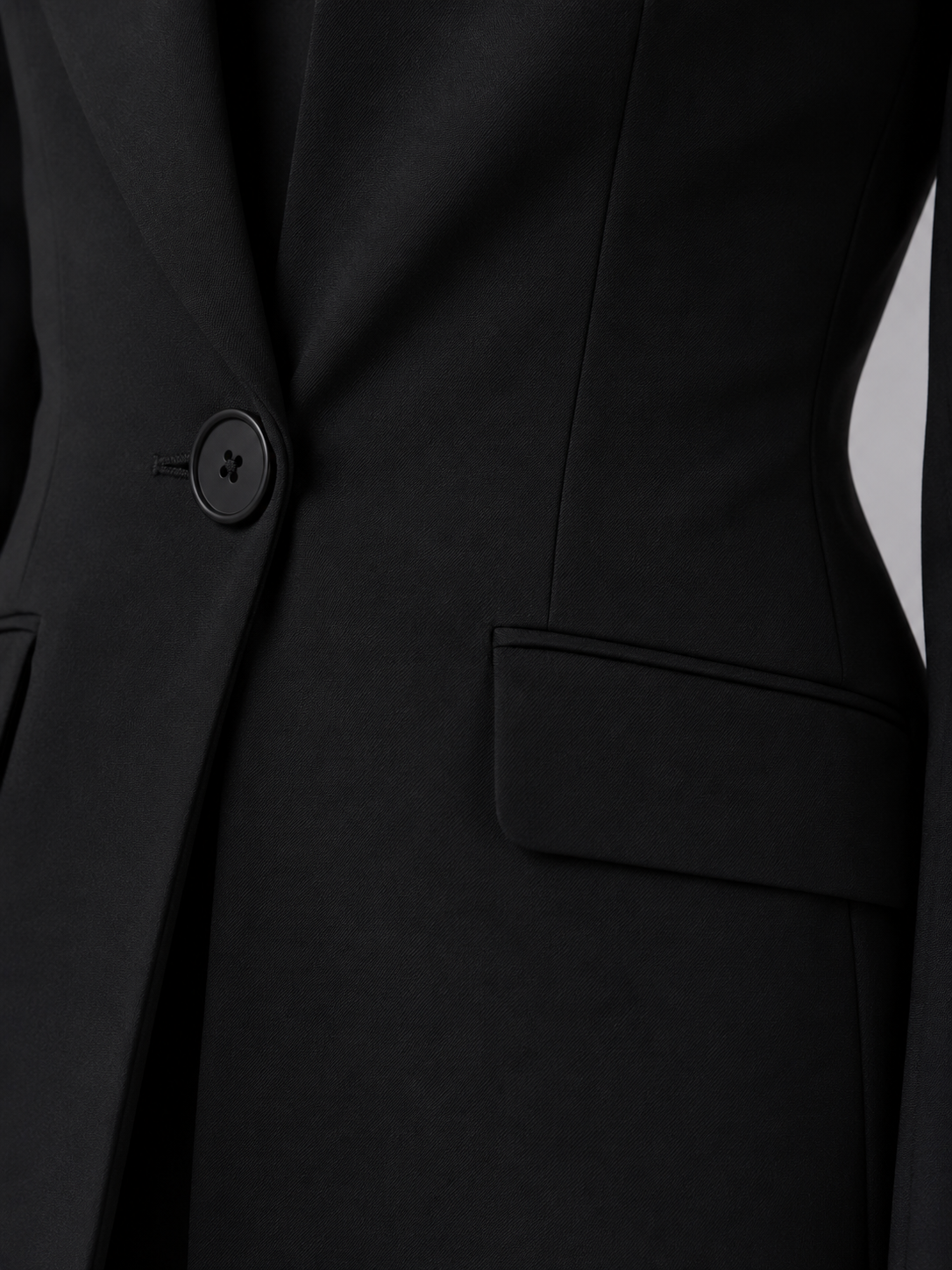 Close-up of a black suit jacket with a button and pocket