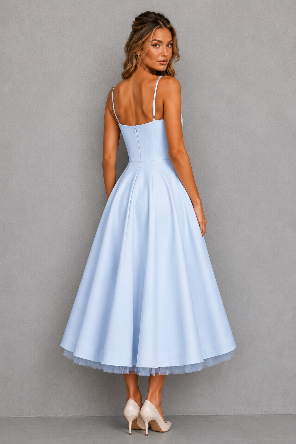 Woman wearing a light blue dress with thin straps against a gray background
