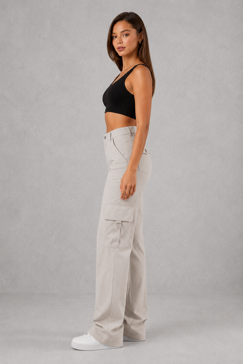 Woman wearing beige cargo pants and a black top on a gray background