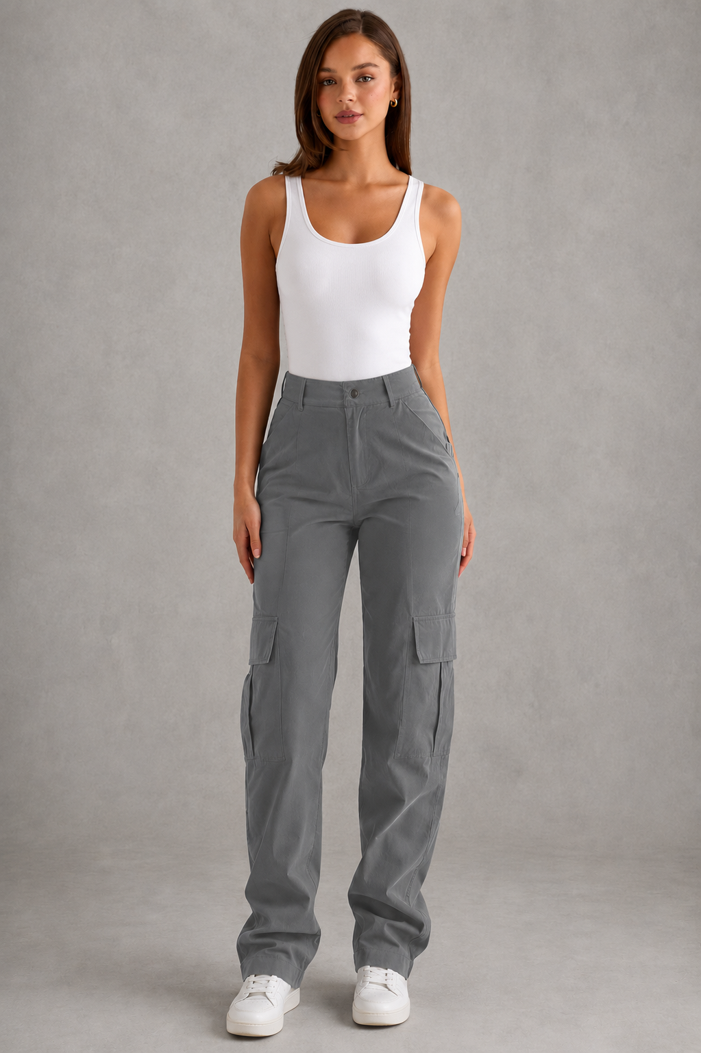 Woman wearing gray cargo pants and a white tank top against a gray background