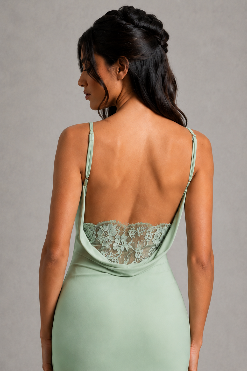 Woman wearing a light green dress with lace detailing on a gray background