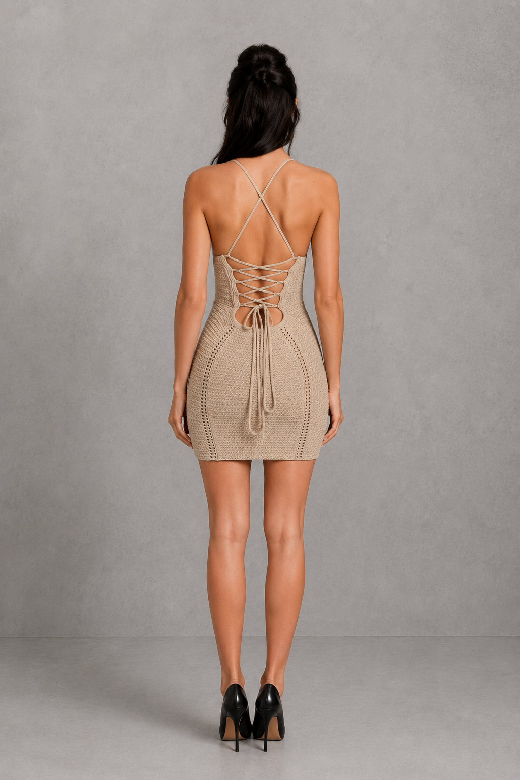 Woman wearing a beige crochet dress with a neutral background