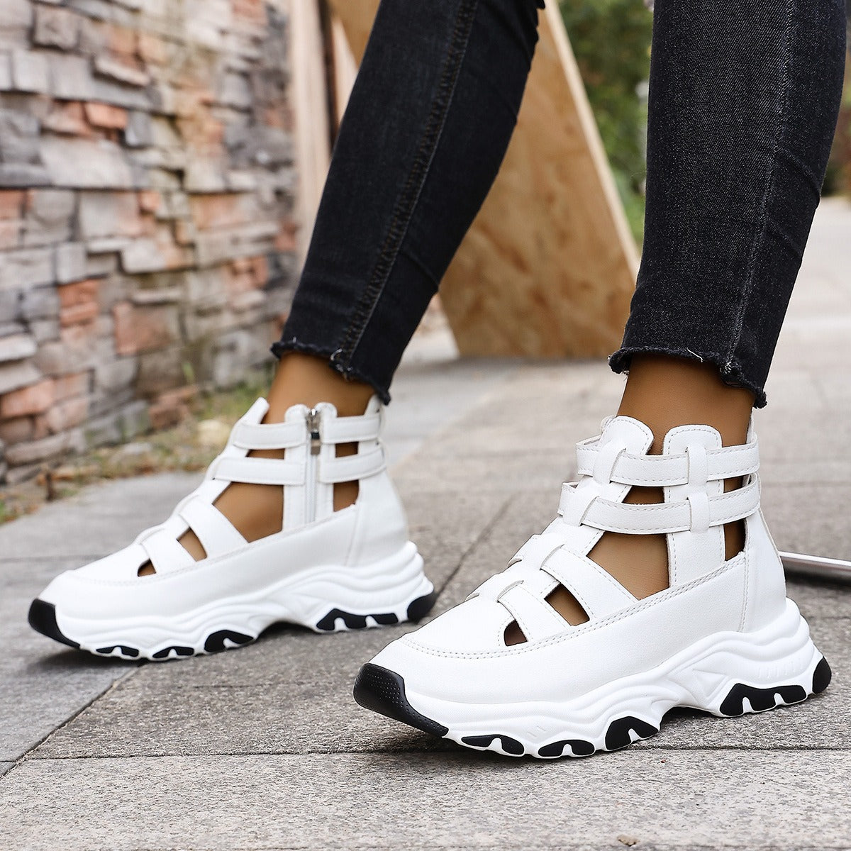 White sneakers with black accents worn by a person on a sidewalk.