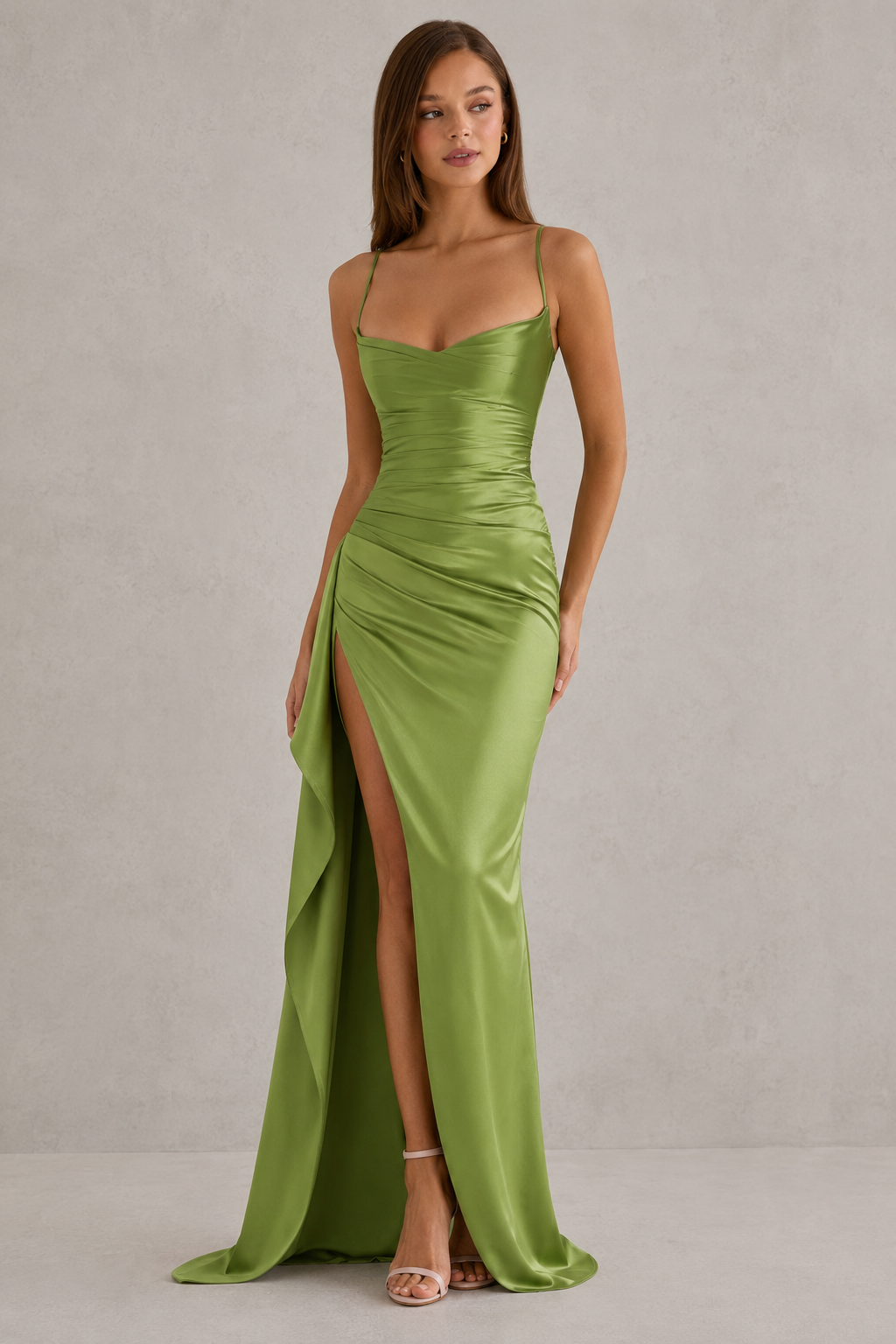Woman wearing a green evening gown with a slit on a plain background