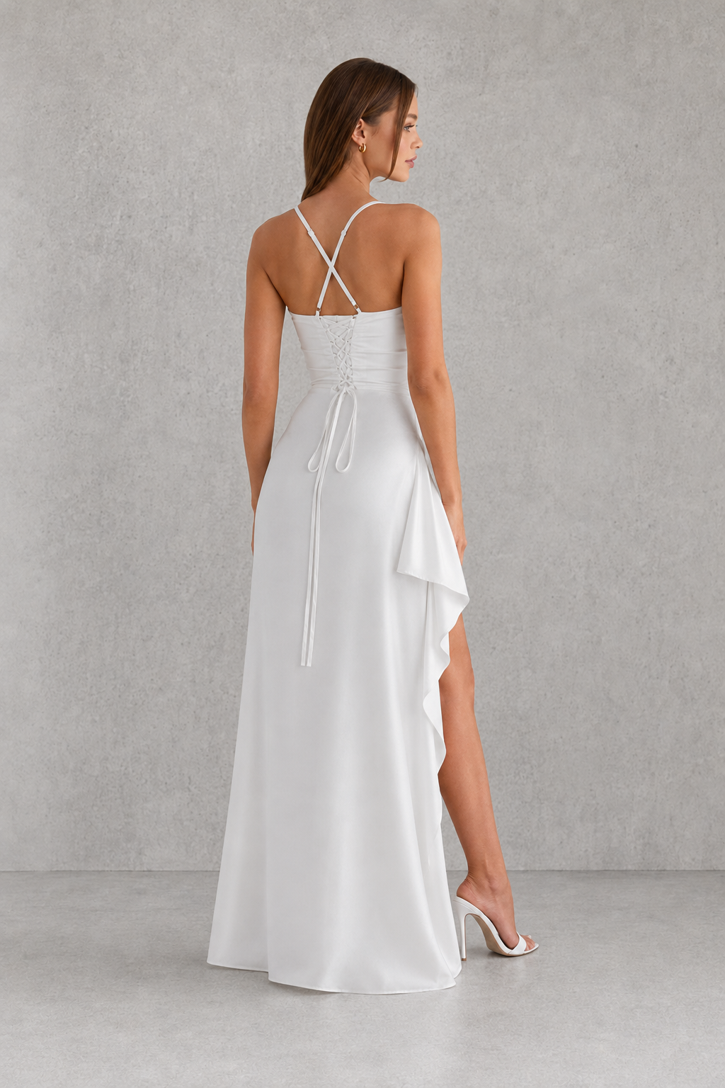 Woman wearing a white dress with thin straps on a gray background