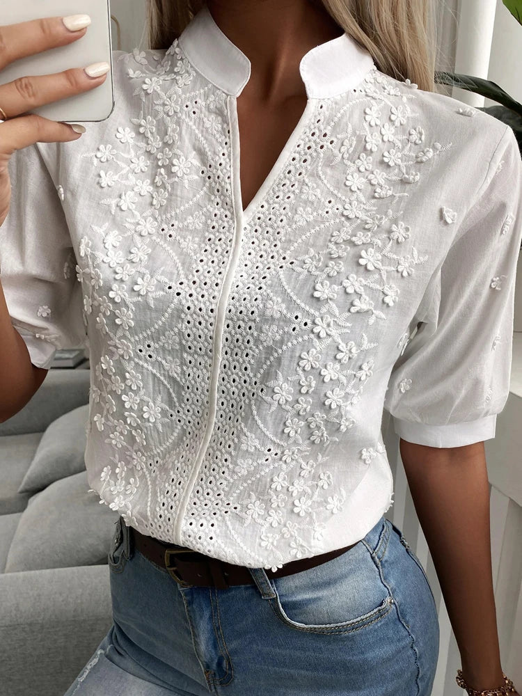 Person wearing a white lace blouse with short sleeves and blue jeans.