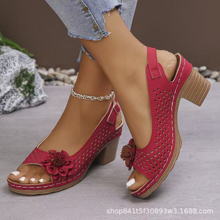 Red sandals with floral details worn by a person on a neutral background