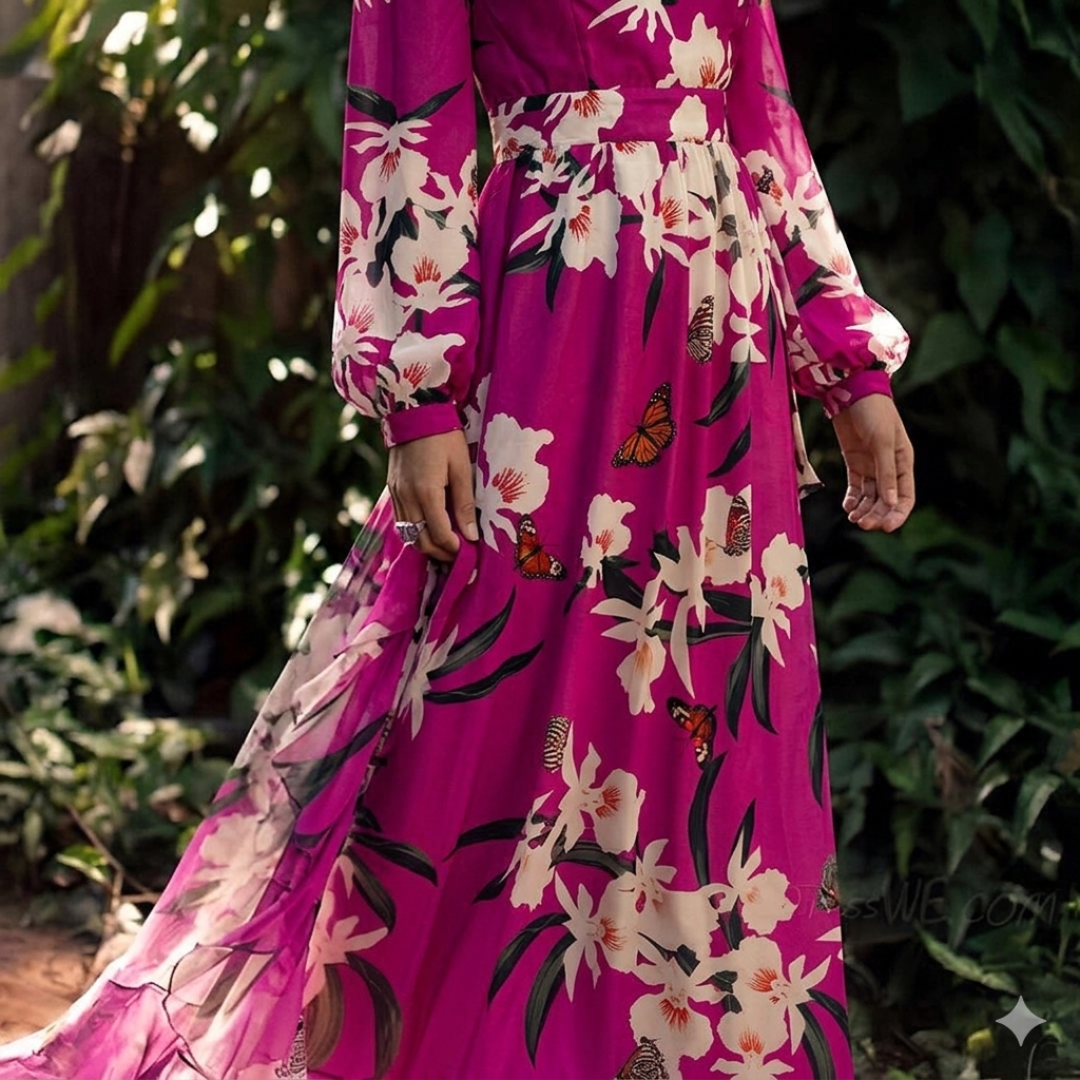 Person wearing a vibrant pink dress with floral and butterfly patterns, standing against a green leafy background.