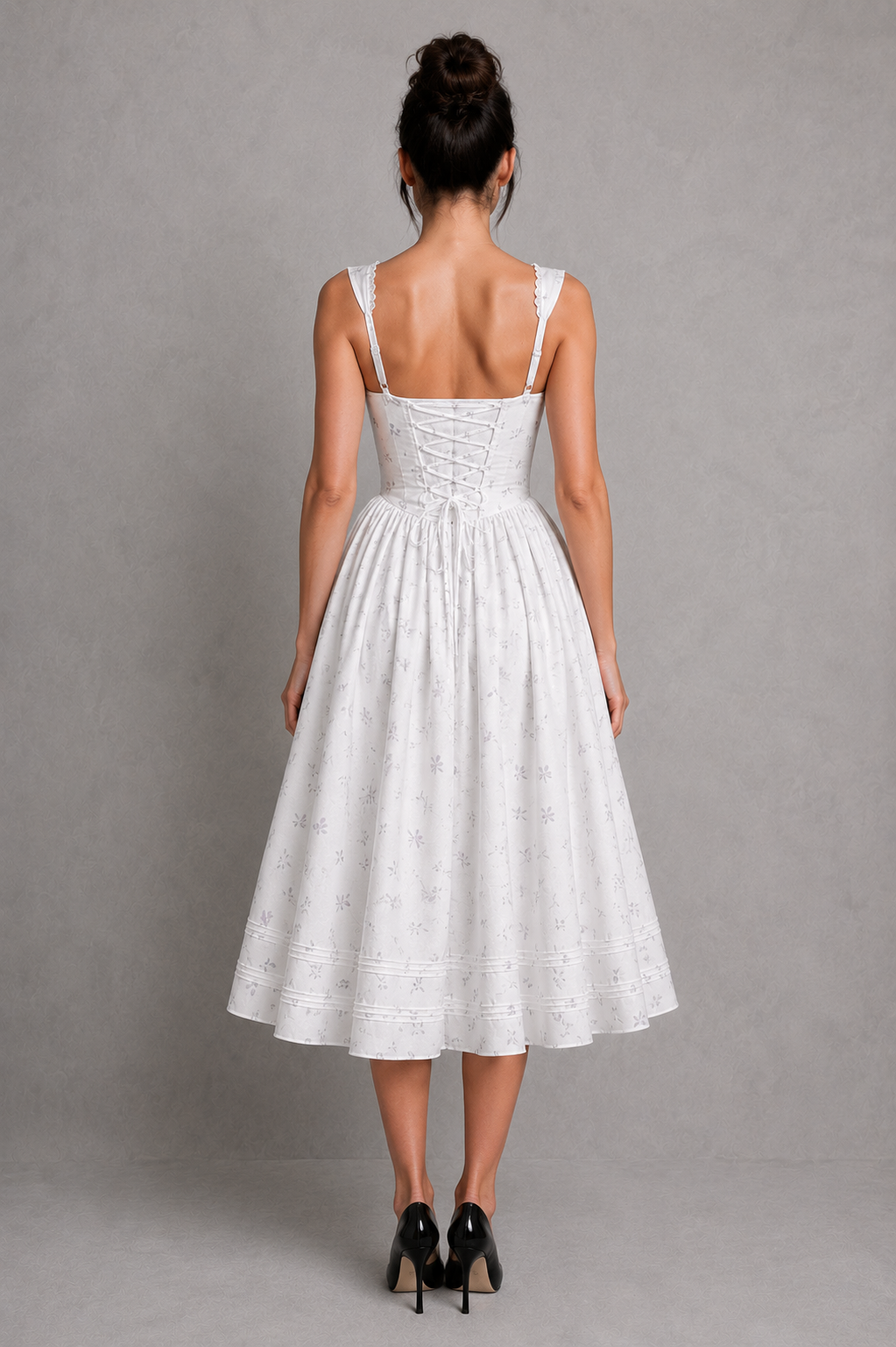 Woman wearing a white dress with thin straps against a gray background