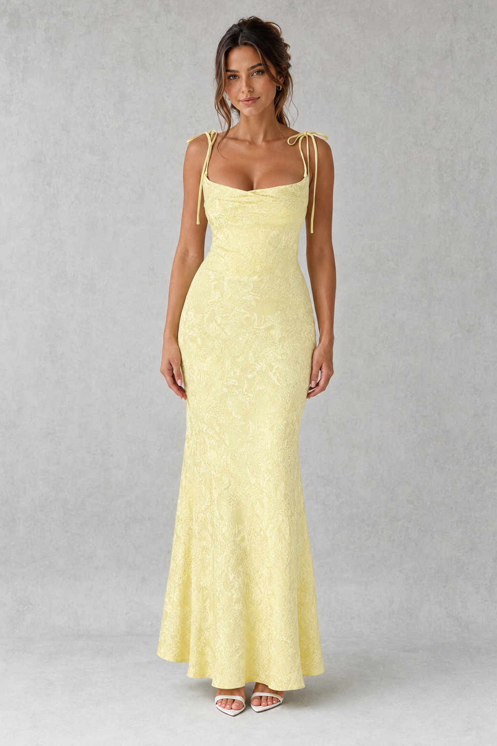 Woman wearing a light yellow evening gown against a gray background