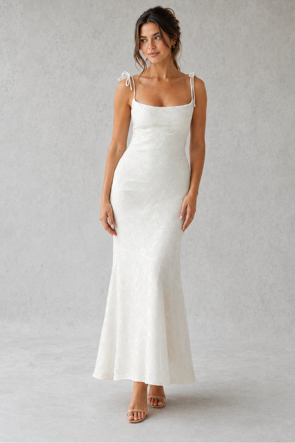 Woman wearing a white slip dress against a plain background
