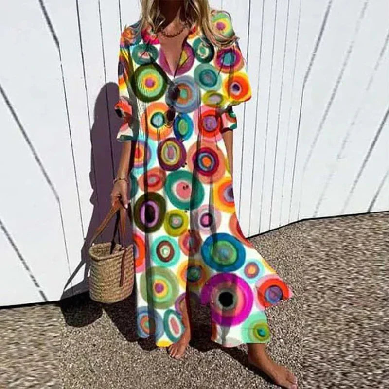 Woman wearing a colorful circular patterned dress against a white wooden fence.