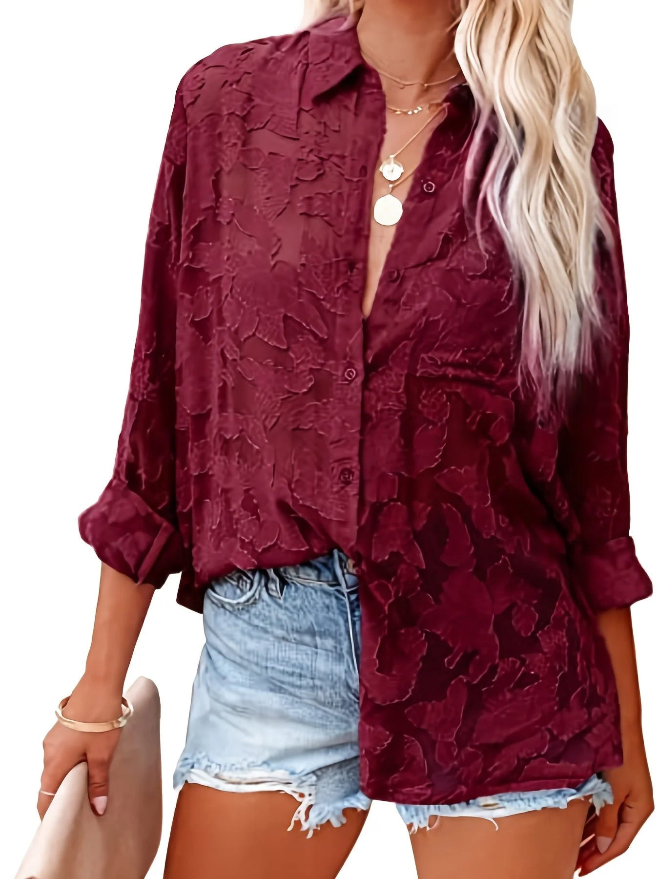 Woman wearing a burgundy textured shirt with denim shorts on a white background