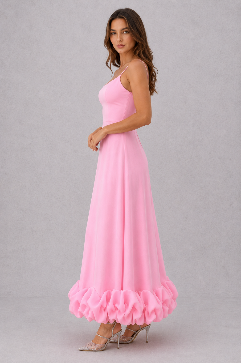 Woman wearing a pink dress with ruffled hem on a gray background