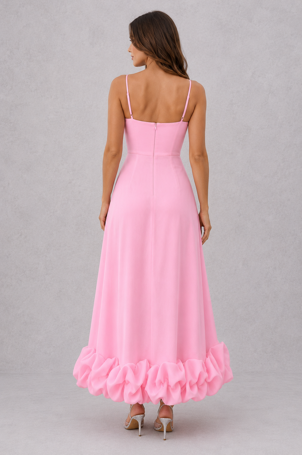 Woman wearing a pink dress with ruffled hem on a gray background