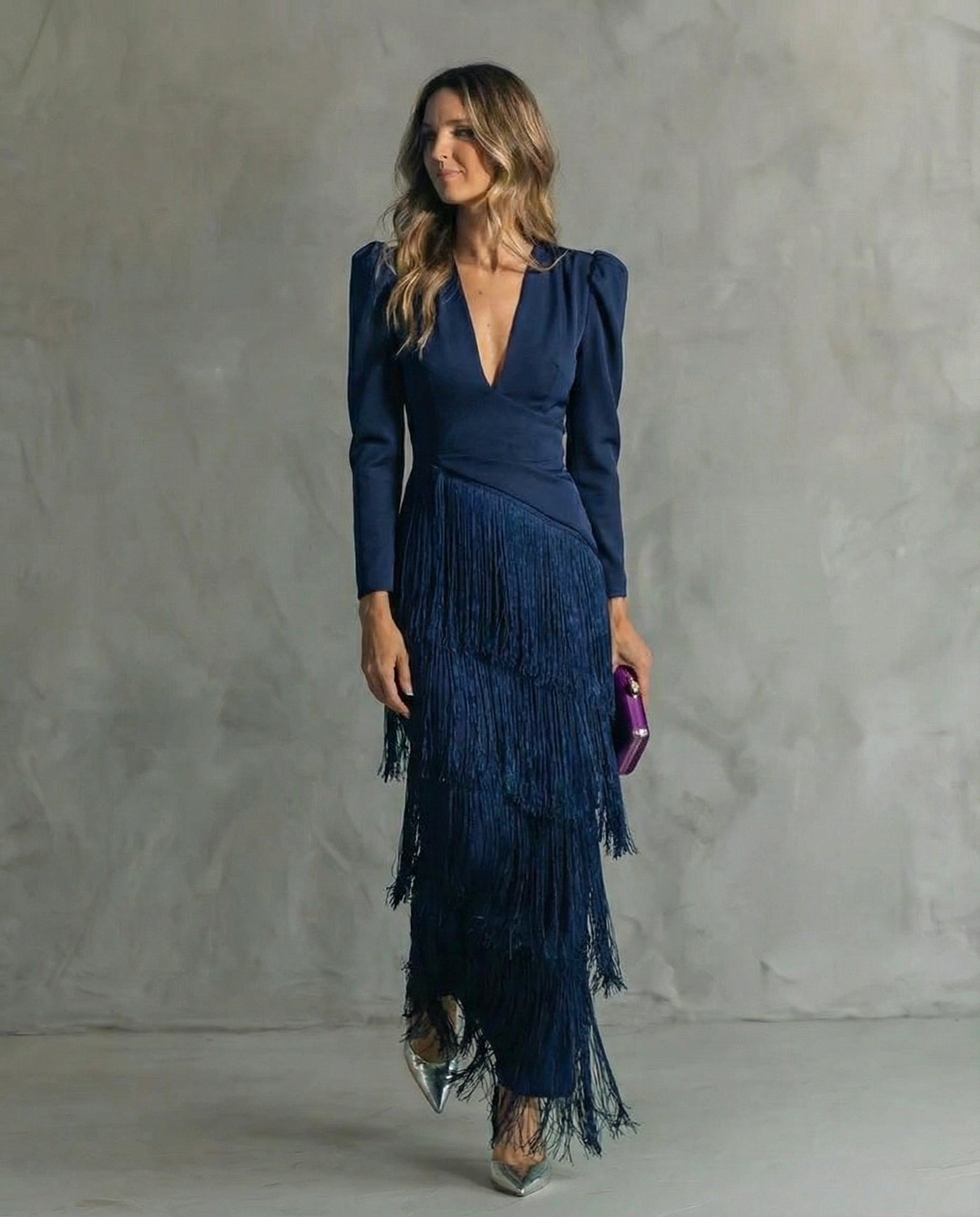 Woman wearing a blue fringe dress against a gray background