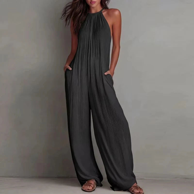 Woman wearing a dark gray jumpsuit against a plain background