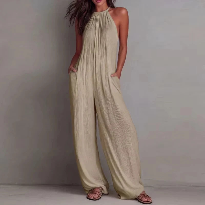 Woman wearing a beige halter neck jumpsuit against a plain background