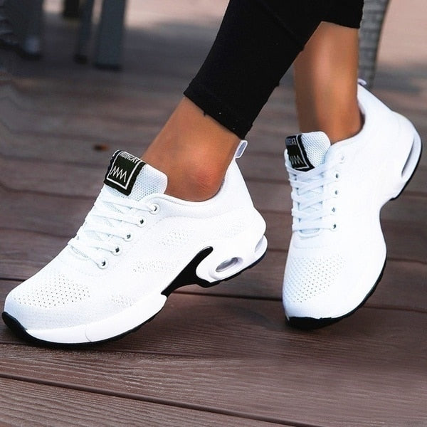 White athletic shoes with black accents on a wooden floor