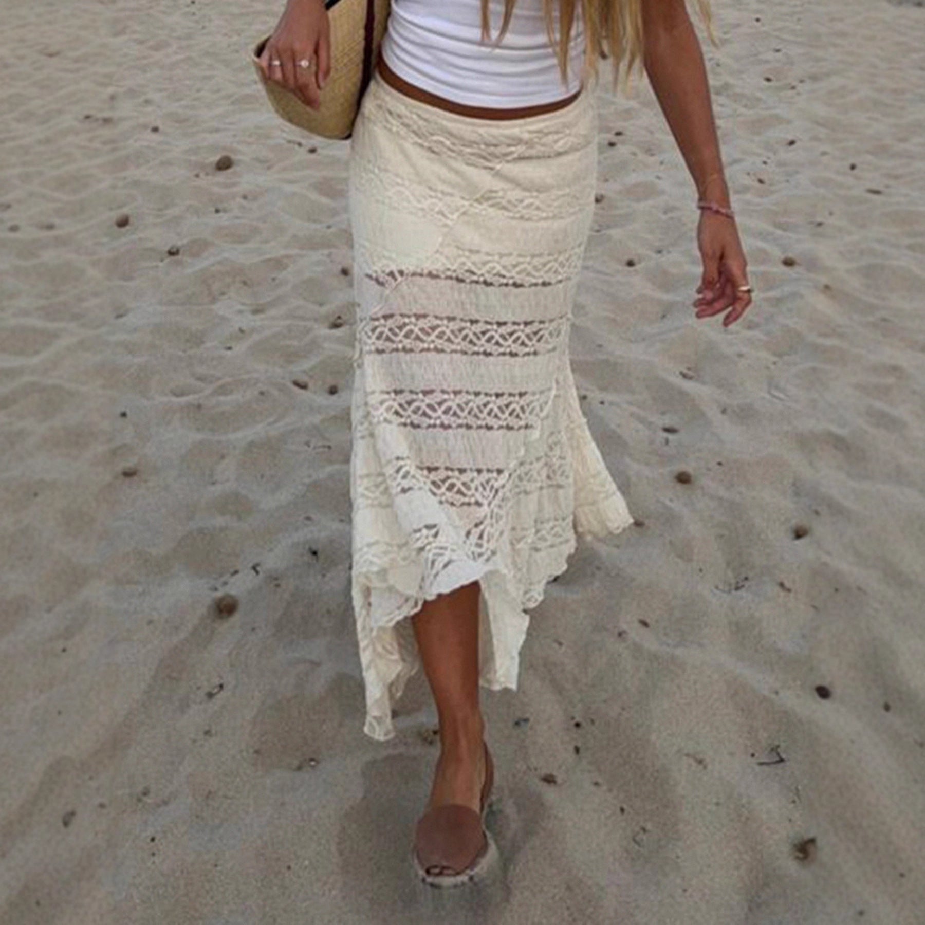 Person wearing a white lace skirt on a sandy beach
