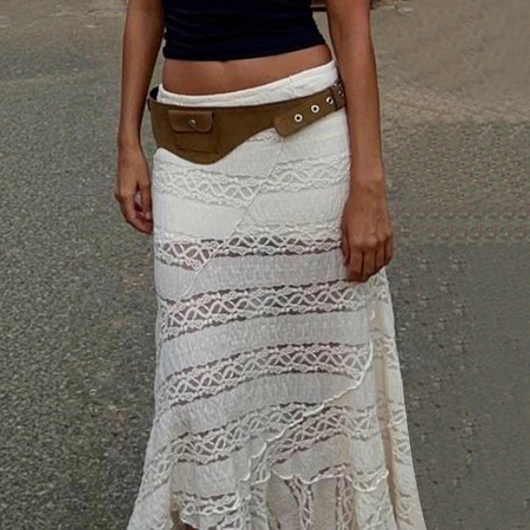 Person wearing a white lace skirt with a brown belt on a gray background