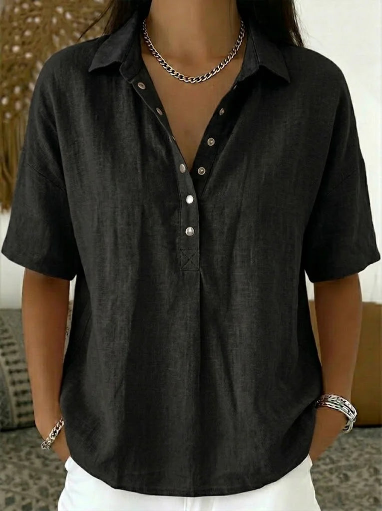 Person wearing a black short-sleeve button-up shirt with a neutral background