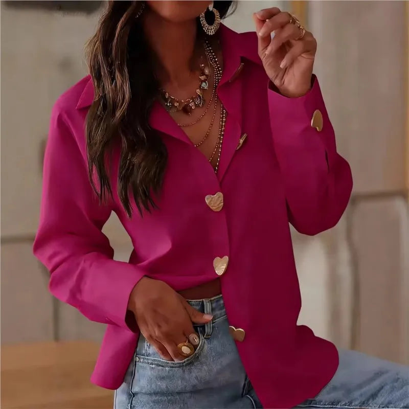 Person wearing a bright pink blouse with heart-shaped buttons and denim jeans.