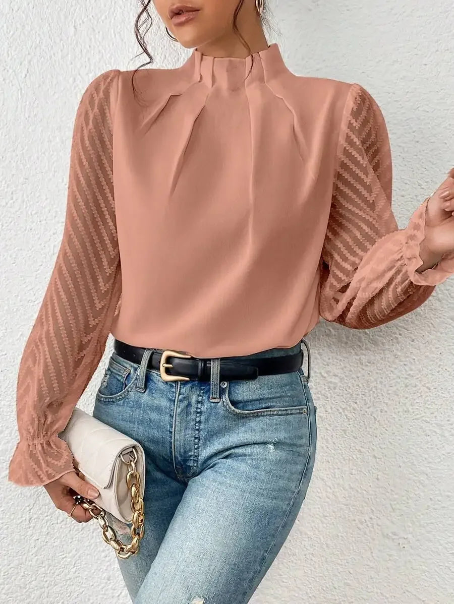 Person wearing a pink blouse with sheer sleeves and blue jeans against a white background