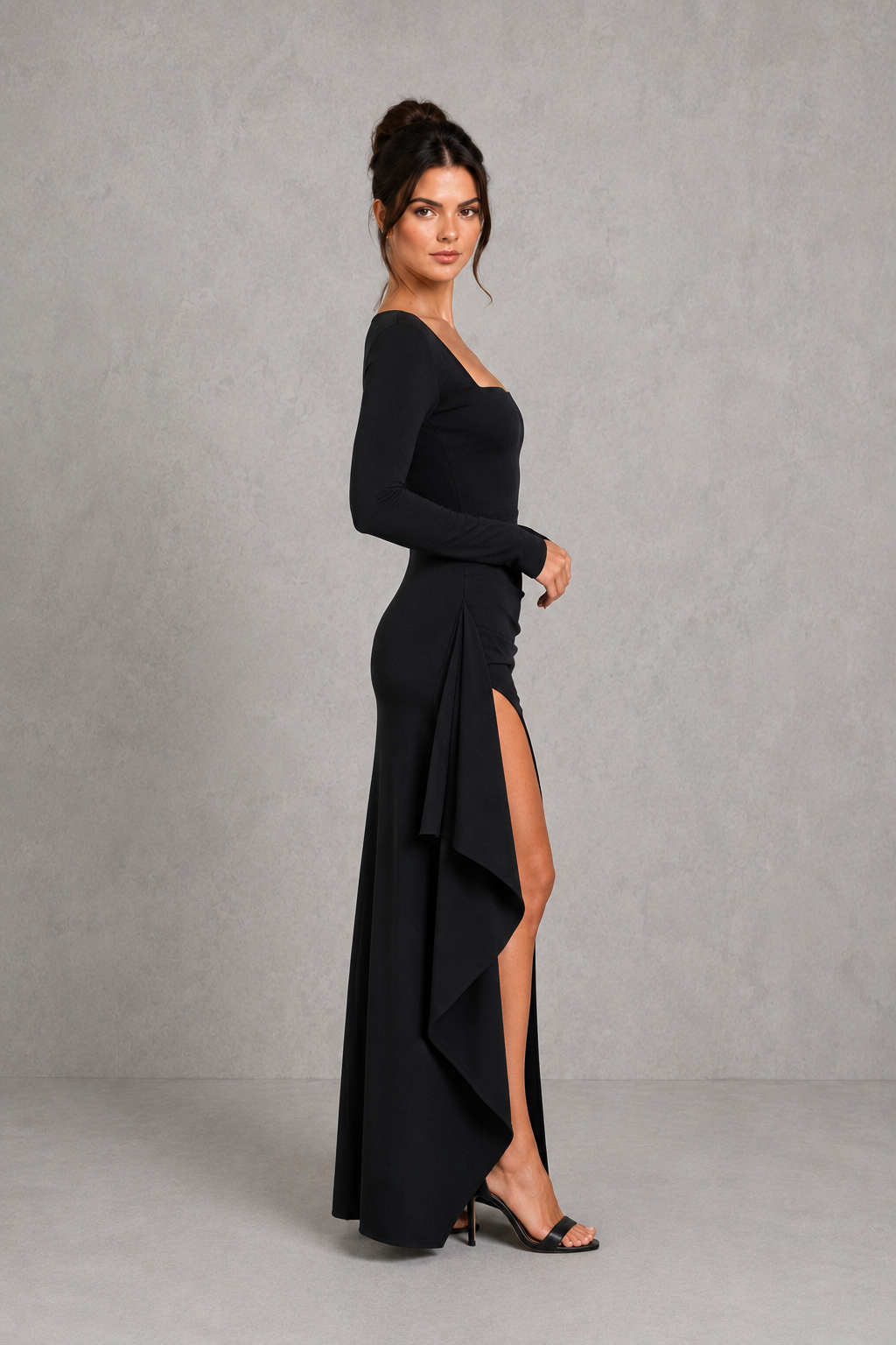 Woman wearing a black evening gown with a slit on a gray background