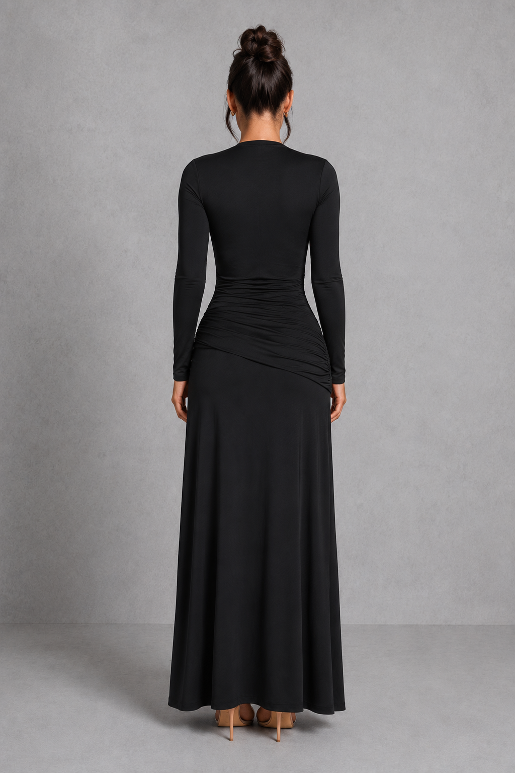 Person wearing a black long-sleeve dress against a gray background