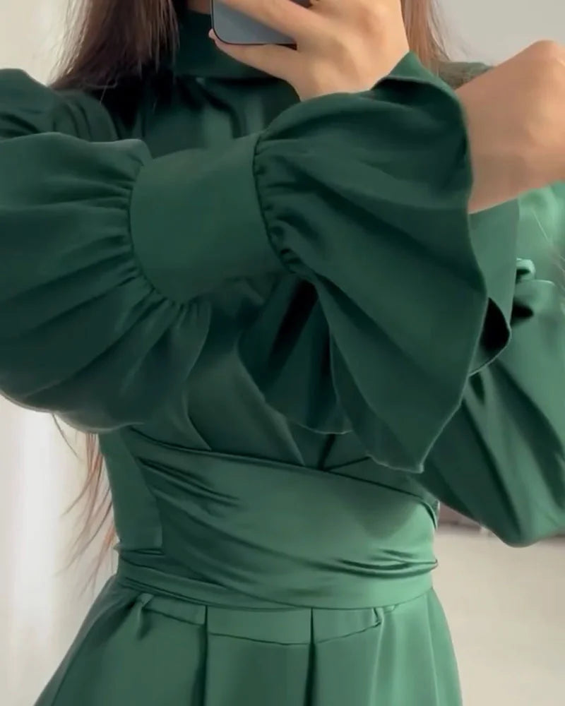 Person wearing a green dress with puffed sleeves in front of a mirror.