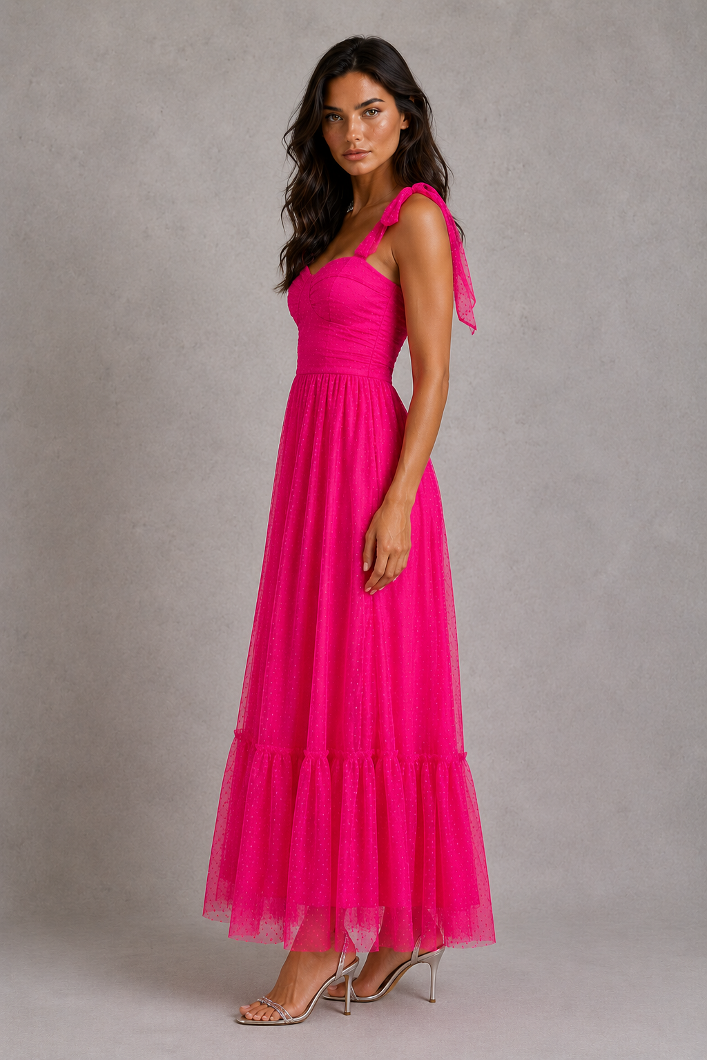 Woman wearing a bright pink one-shoulder dress against a gray background