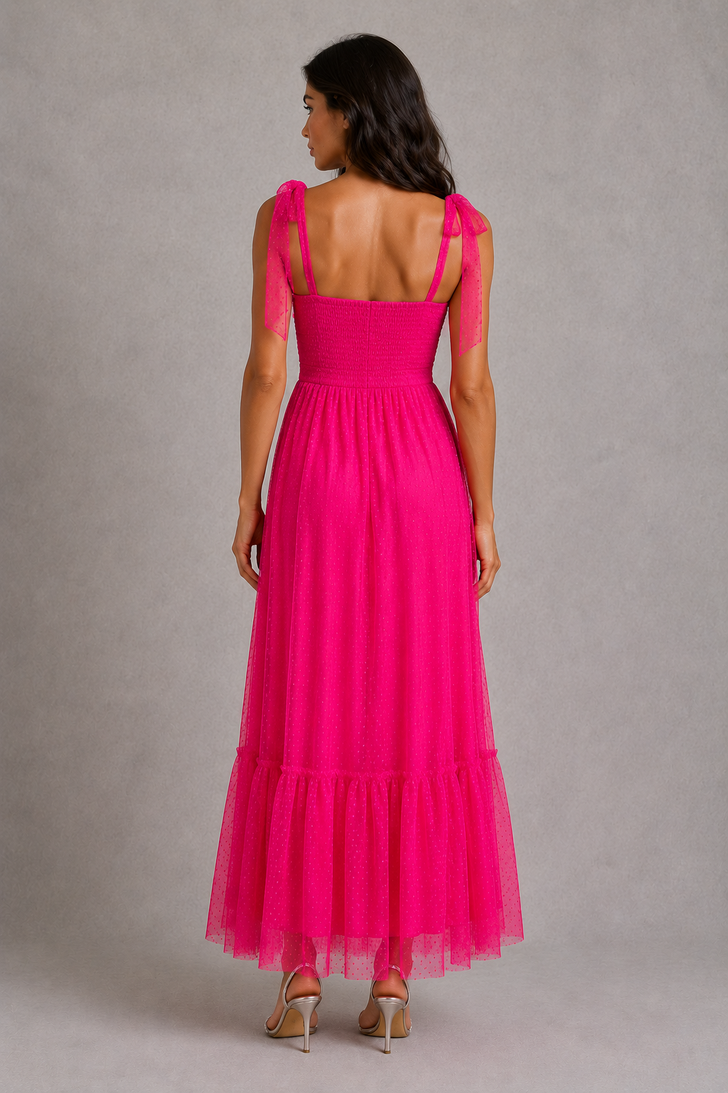 Woman wearing a pink dress with sheer sleeves against a gray background
