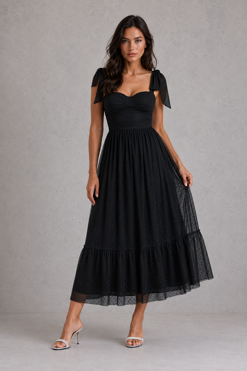 Woman wearing a black dress with bow sleeves against a gray background