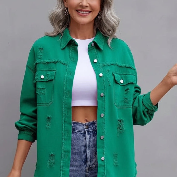 Woman wearing a green denim jacket and blue jeans against a gray background