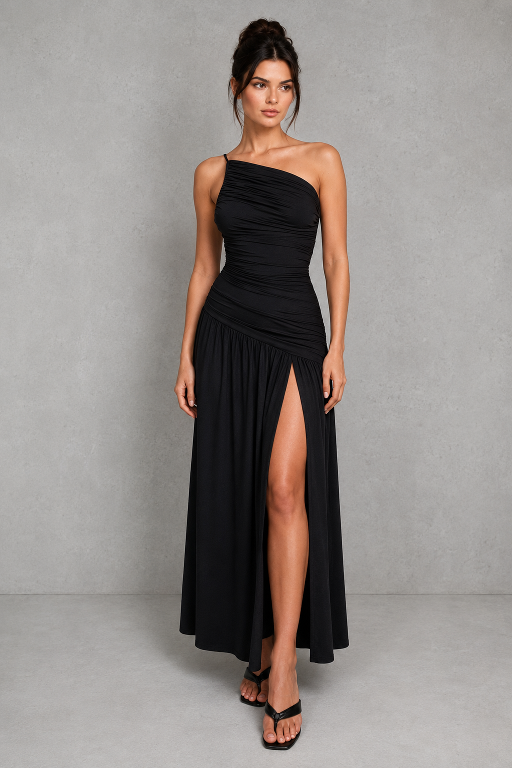 Woman wearing a black one-shoulder dress with a slit on a gray background