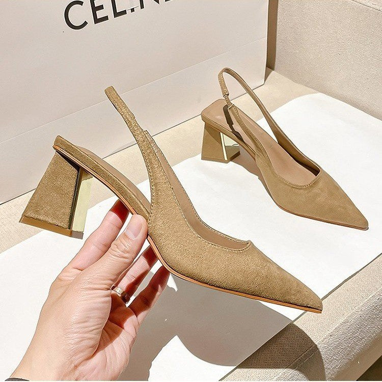 Beige high-heeled shoes held by a hand with a beige box in the background