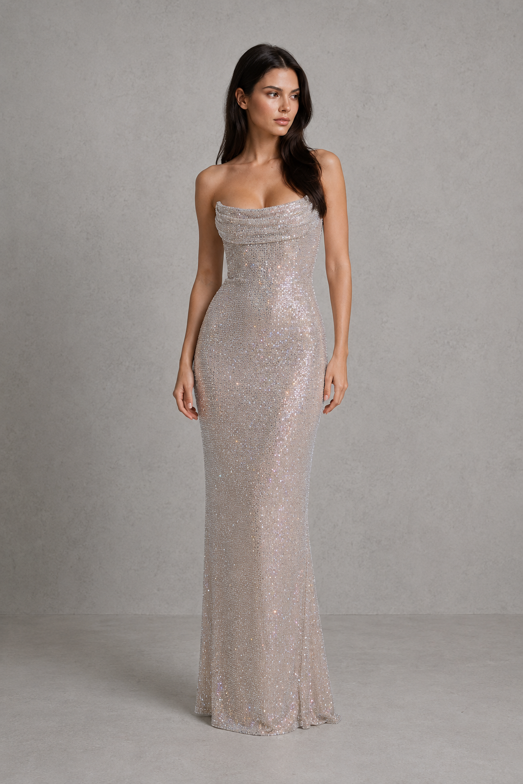 Woman wearing a strapless, long, silver sequin dress against a gray background