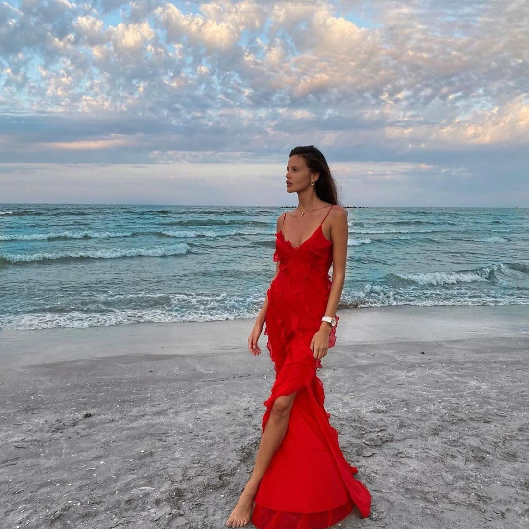 Woman in a red dress standing on a beach with ocean and sky in the background