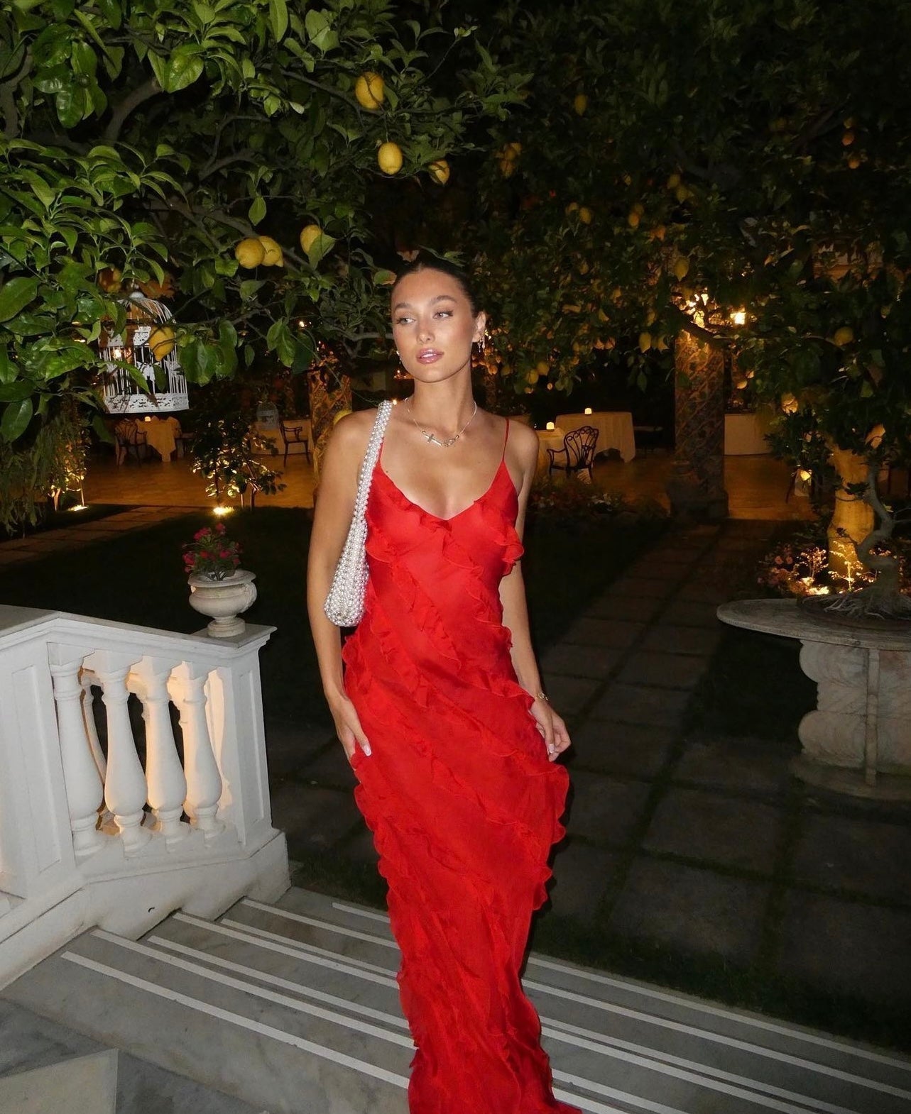 Woman in a red dress standing outdoors with trees and lanterns in the background