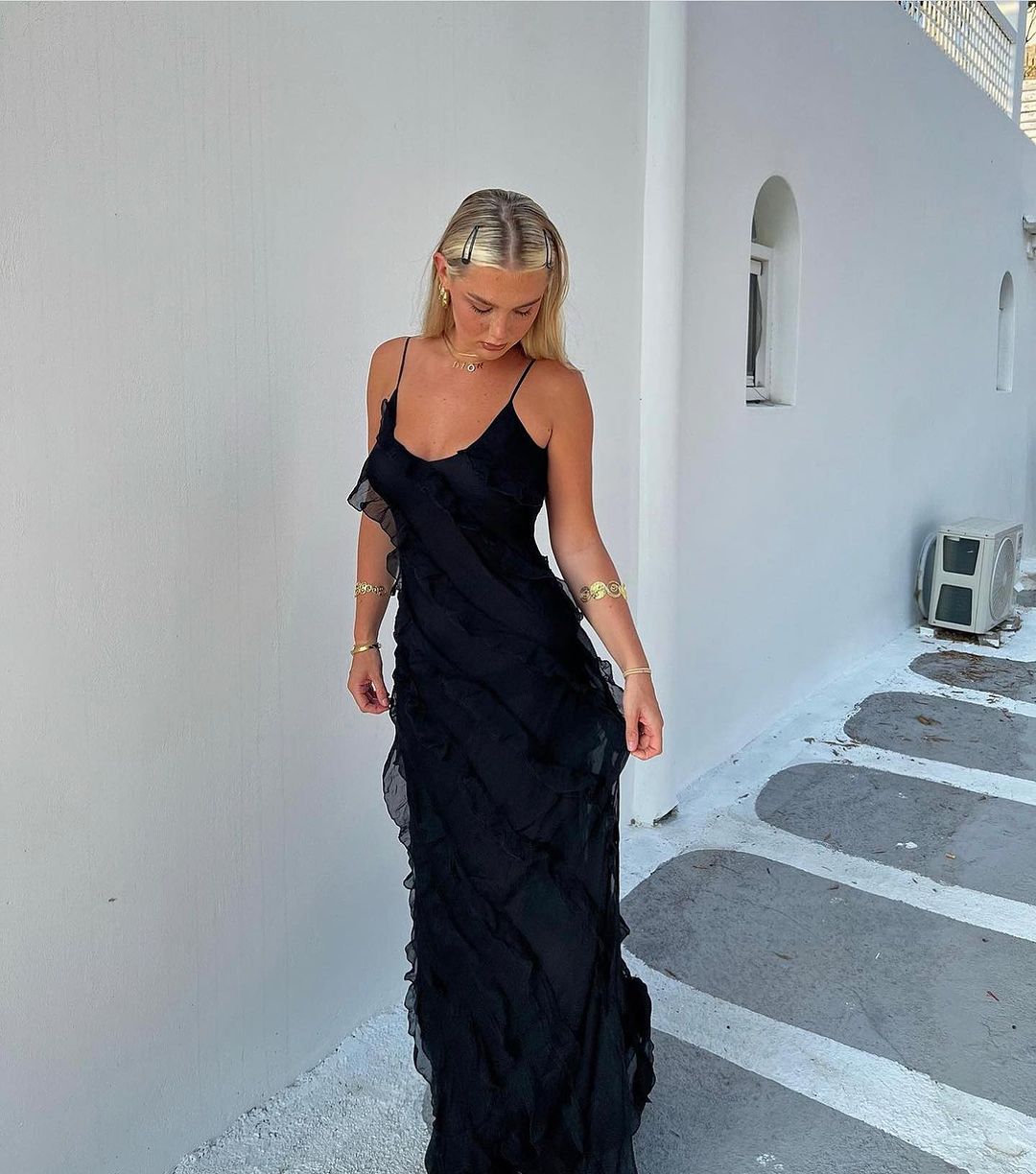 Woman in a black evening gown standing on a white pathway.