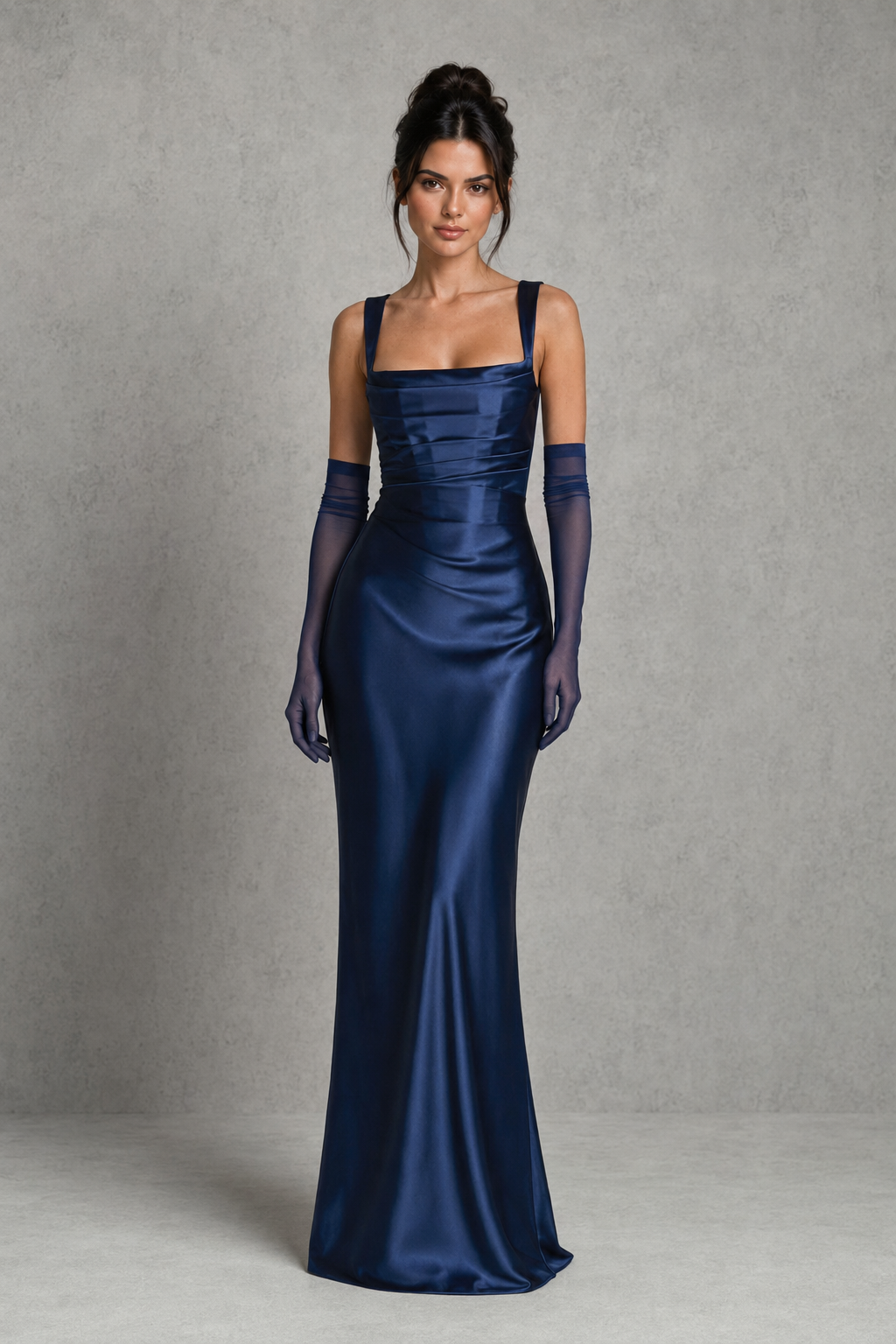 Woman wearing a navy blue evening gown with matching gloves against a gray background