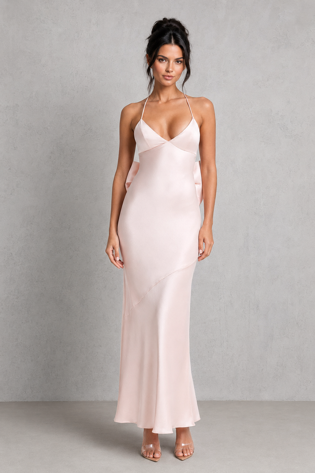 Woman wearing a long, light pink satin dress against a gray background