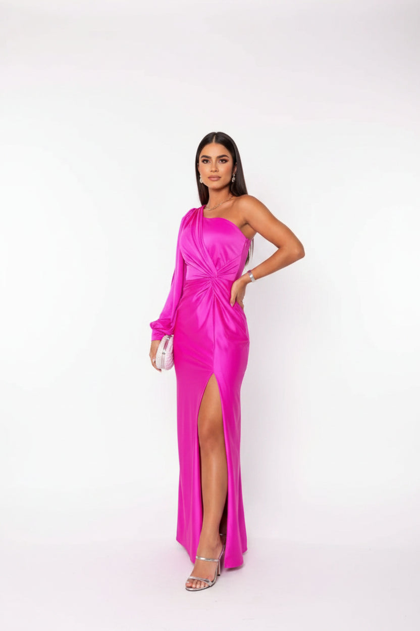 Woman in a bright pink one-shoulder dress standing in a modern interior setting.